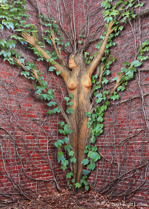 Ivy Dryad - A brick interior corner is covered with ivy vines.  In the center of them a dryad is manifesting, with extra arms forming like ivy vines and new green leaves projecting outwards from her.