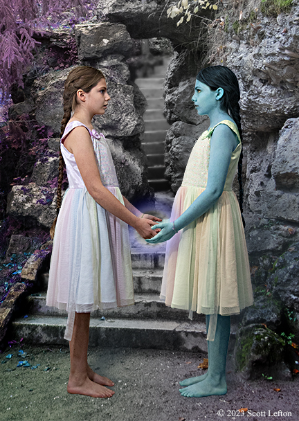 Two young girls facing each other and holding hands. One girl  has blue skin. A glow is forming around their hands.